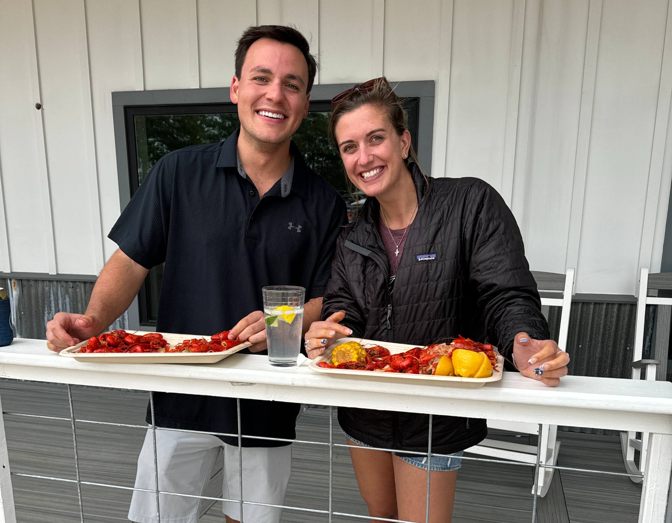 An image of 2 guests enjoying crawfish on the main building wrap around deck at our community event