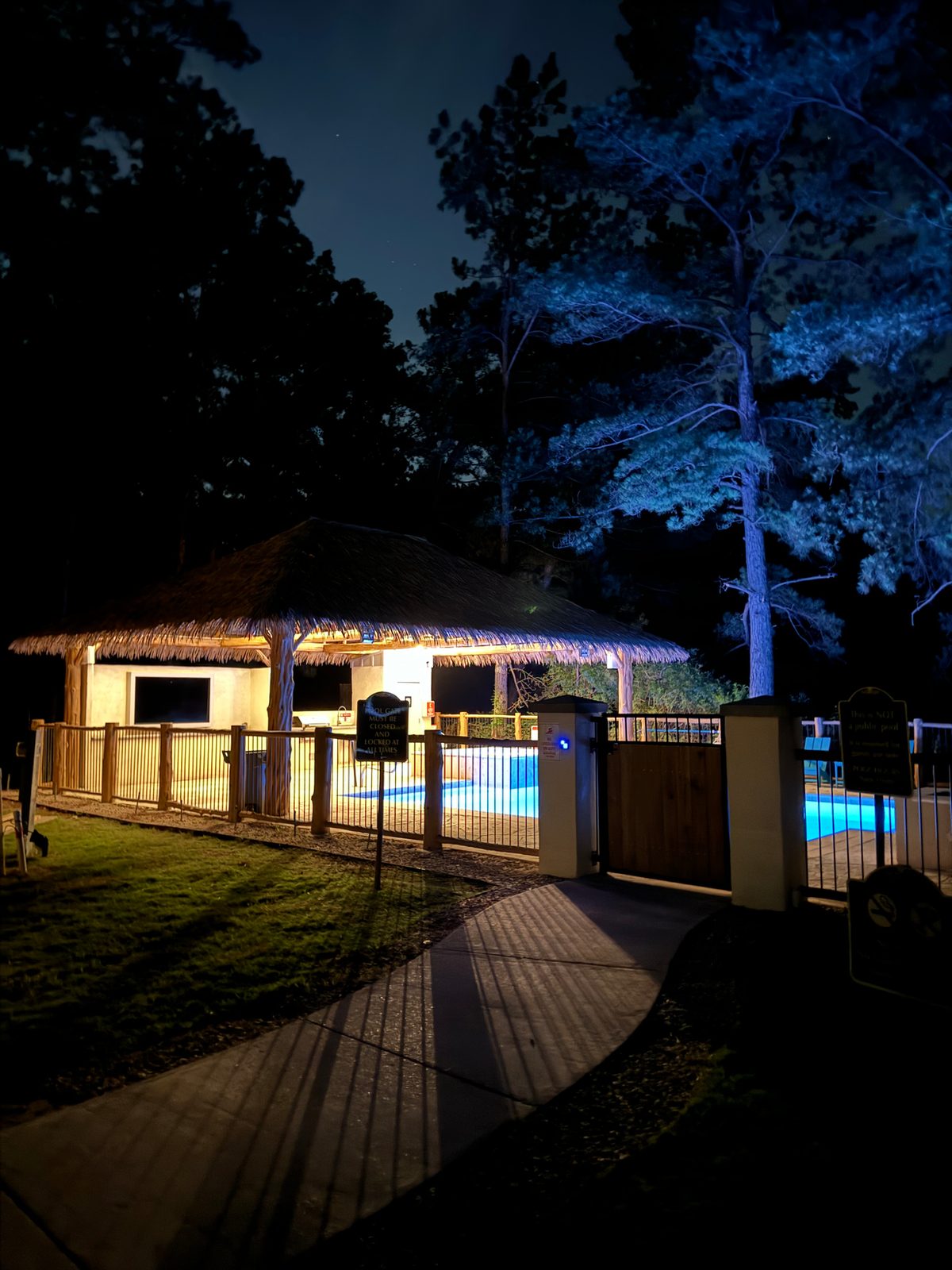The pool and spa lit up at night behind the gated entrance