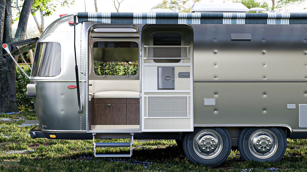 A picture of an aluminum camper airstream with its awning out.